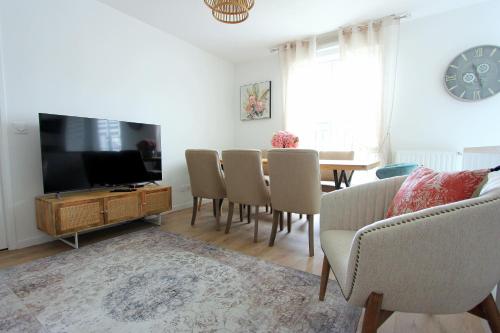 un salon avec une télévision et une table avec des chaises dans l'établissement ELBE2 Apartment 8ppl gateways to Disneyland Paris, à Serris