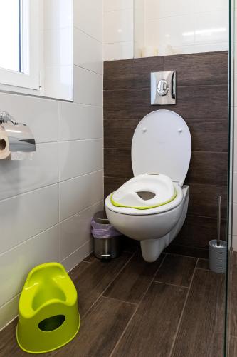 a bathroom with a toilet and a green stool at Baka Apartman in Ábrahámhegy