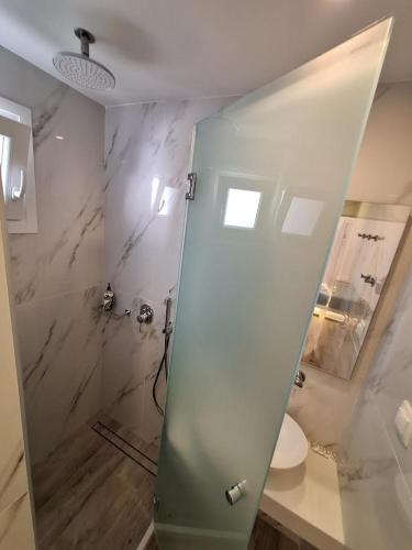 a bathroom with a shower with a glass door at Alexandra Suites & Rooms - MYKONOS PORT in Mýkonos City