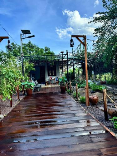 a wooden walkway leading to a house with trees at Homestay Chuyện Của Nắng - Nang's Story in Phố Trạch
