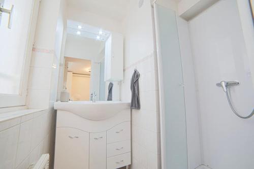 une salle de bain blanche avec un lavabo et un miroir dans l'établissement Duplex cosy à Rouen au cœur du centre historique, à Rouen