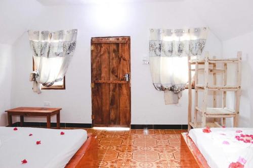 a room with two beds and a wooden door at New Jambo Bungalows in Paje