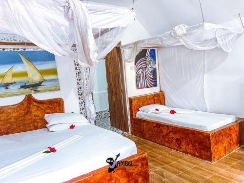 due letti in una stanza con tende bianche di New Jambo Bungalows a Paje