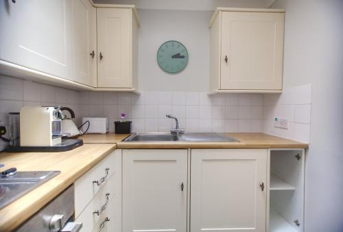 a kitchen with white cabinets and a clock on the wall at Sea Mist - Hastings in Hastings