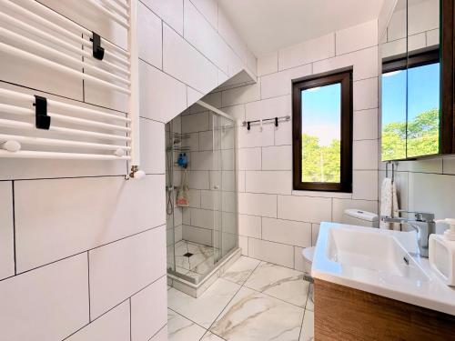 a white bathroom with a sink and a window at VILLA EVA - 5 min to the beach in Shekhvetili