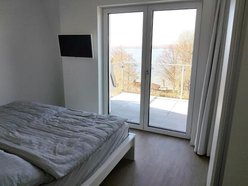 a bedroom with a bed and a sliding glass door at Neubau-Ferienwohnung mit Panorama-Seeblick in Bosau
