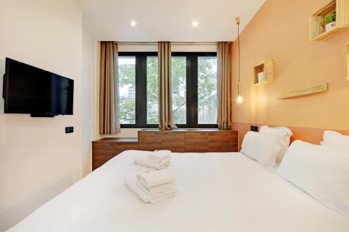 - une chambre avec un lit blanc et une télévision à écran plat dans l'établissement Pick A Flat's Apartment in Reuilly-Diderot - Rue Claude Tillier, à Paris