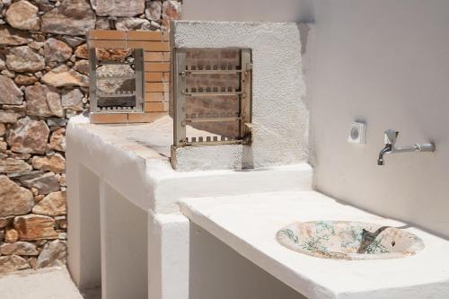 a bathroom with a sink and a stone wall at The Stone Project in Ermoupoli