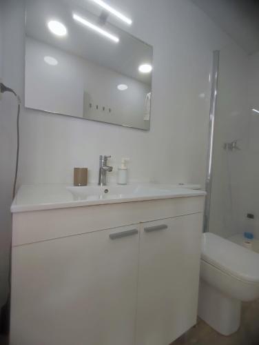 Un baño blanco con lavabo e inodoro. en Bright loft near the sea BIKES, en Valencia
