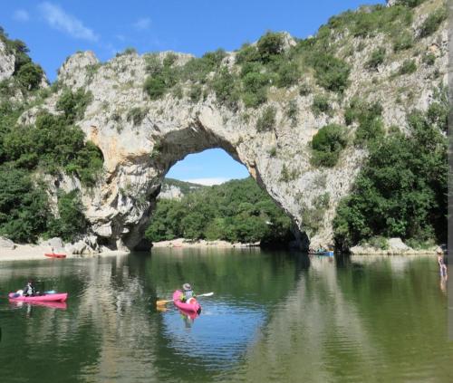 un groupe de personnes en kayak dans l'eau sous une arche dans une rivière dans l'établissement Faites une pause, à Saint-Gineis-en-Coiron