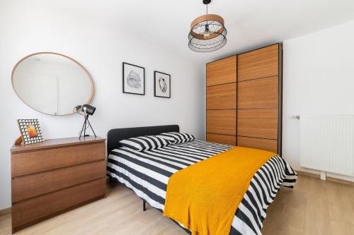 - une chambre avec un lit, un miroir et une commode dans l'établissement Charmant 2 pièces Paris Pleyel- Stade de France, à Saint-Denis