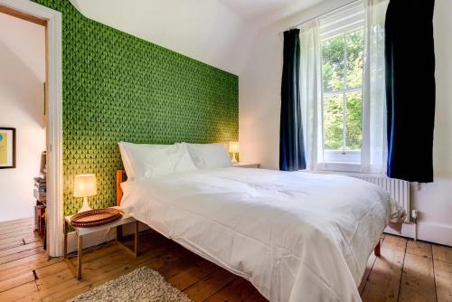 a bedroom with a white bed and a green wall at The Writers Retreat- Hastings in Hastings