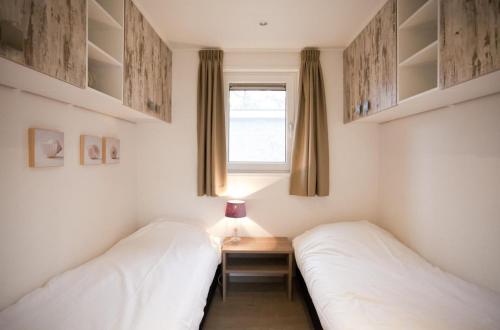 two beds in a room with a table and a window at EuroParcs Bad Hoophuizen in Hulshorst
