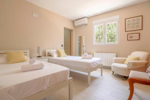 a bedroom with two beds and a chair and a window at Casa Angilaga in Jávea