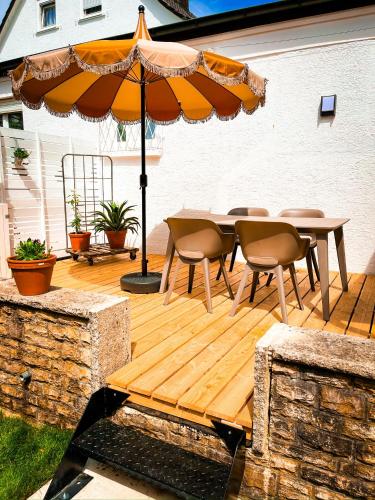 a wooden deck with a table and an umbrella at Hacienda Flats - Wunderschöne Ferienwohnungen am Seewald in Friedrichshafen