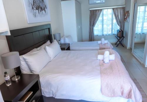 a bedroom with two beds with white sheets and towels at Ulifalodge & functions in Durban