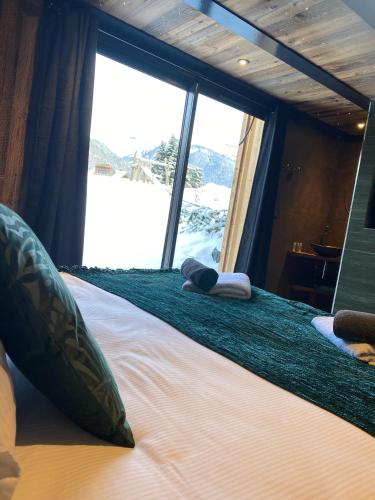 a large bed in a room with a large window at Les Mazots des Fées in Morzine
