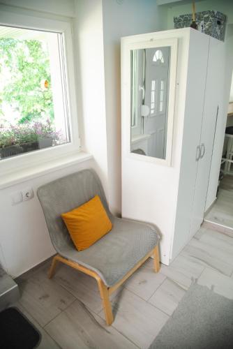 a chair with an orange pillow sitting in a room at Apartmani Maslačak in Vrdnik