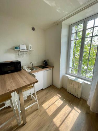 une cuisine avec une table en bois et une grande fenêtre dans l'établissement STUDIO parfaitement agencé, à Lamballe