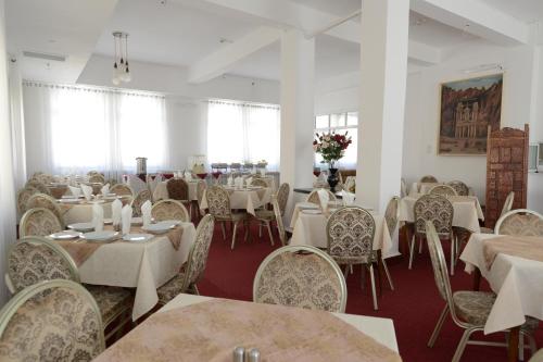 uma sala de jantar com mesas e cadeiras brancas e mesas brancas e chairsktop em Rivoli Hotel Jerusalem em Jerusalém