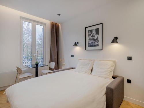 une chambre avec un grand lit blanc et une fenêtre dans l'établissement Charming Studio in Pantin, à Pantin