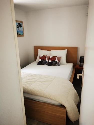 une chambre avec un lit avec des draps blancs et des oreillers dans l'établissement Maison de vacances climatisée, à Saint Pierre La Mer