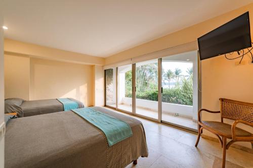 a bedroom with a bed and a television and a chair at 2029 - Villa Camino Real in Santa Cruz Huatulco