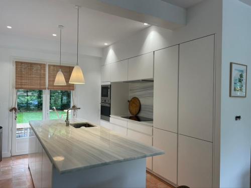 une cuisine avec des armoires blanches et un comptoir dans l'établissement Villa Victoire, à Lège-Cap-Ferret