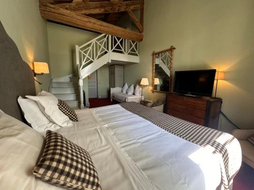 a bedroom with a large white bed and a television at Le Mas de Peint - Hôtel et Restaurant in Le Sambuc