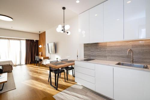 a kitchen with white cabinets and a wooden table at West 21 Tower in Fontana