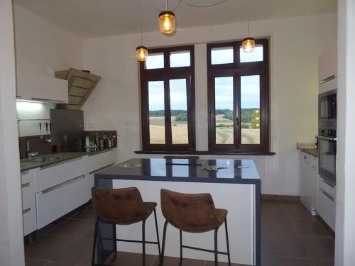 une cuisine avec deux tabourets de bar et un comptoir avec deux fenêtres dans l'établissement maison de famille, à Driencourt
