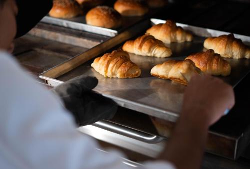 a person taking a tray of croissants out of an oven at Aleenta Hua Hin - Pranburi - The Small Luxury Hotels of the World in Pran Buri