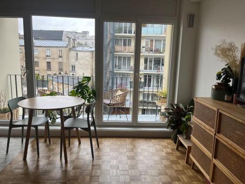 une table et des chaises dans une pièce avec une grande fenêtre dans l'établissement Confortable studio Canal st Martin, à Paris