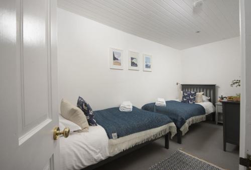 two beds in a room with white walls at Cob Cottage in St. Agnes