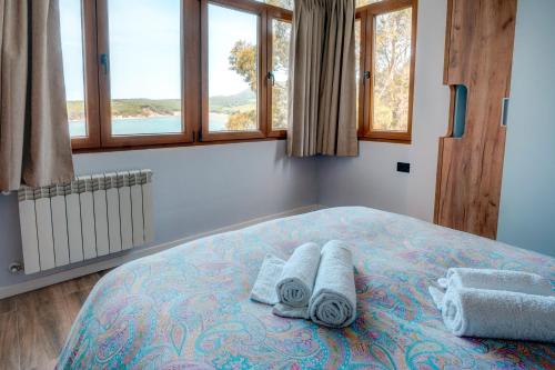 a bedroom with a bed with towels and windows at El mirador de Mogro in Mogro