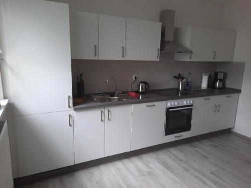 a kitchen with white cabinets and a sink at Ferienwohnung im Hotel in Eicklingen