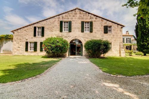 an old stone house with a gravel driveway at Le Mas de Peint - Hôtel et Restaurant in Le Sambuc