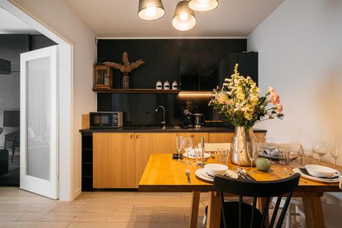 a kitchen with a wooden table with a vase of flowers at Pod Gubałówką - LoftAffair in Zakopane