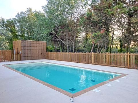 - une piscine dans un jardin avec une clôture en bois dans l'établissement Appart 4 pers climatisé parking piscine proche des plages ménage inclus - V0816, à Vias
