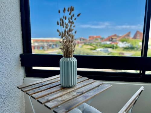 un vase assis sur une table devant une fenêtre dans l'établissement Dune Dreamer - Appartement beach front, à Seignosse
