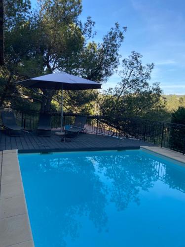 - une piscine bleue avec un parasol et des chaises dans l'établissement Maison de Golfeur, à Mallemort