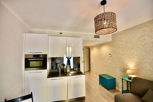 une cuisine avec des armoires blanches et un salon dans l'établissement Nice Signature Cours Saleya, à Nice