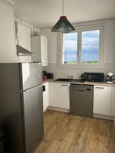 une cuisine avec des armoires blanches et un réfrigérateur en acier inoxydable dans l'établissement Appartement La Perle Urbaine, à Bourges