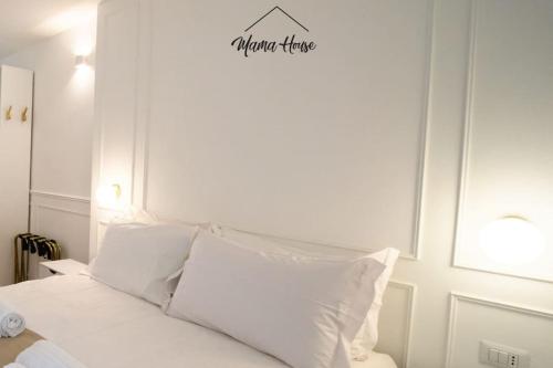 a white bed with white pillows and a sign above it at Mama House Cenisio in Milan