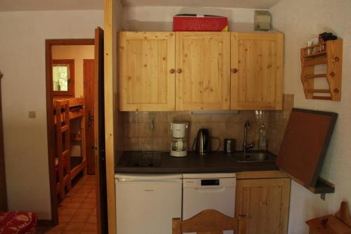Elle comprend une petite cuisine avec des placards en bois et un évier. dans l'établissement VOINETTES VNB2 TELECABINE & MOUNTAIN 4 Pers, à Châtel