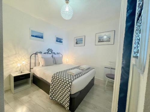 une chambre blanche avec un lit et une table dans l'établissement PGH N15 - Vue Mer, Première Ligne & Parking Privé, à La Grande Motte