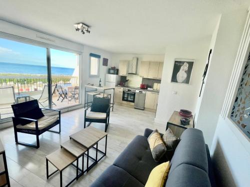 un salon avec un canapé bleu et une cuisine dans l'établissement PGH N15 - Vue Mer, Première Ligne & Parking Privé, à La Grande Motte
