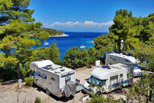 two rvs parked next to the water with trees at Kamp Vira Mobile Homes in Hvar