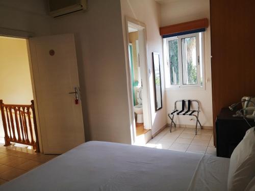 a bedroom with a bed and a window and a chair at St Elena Boutique Residence in Larnaka