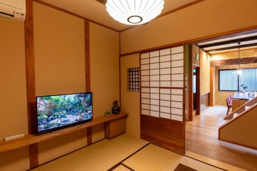 a living room with a flat screen tv and white walls at Suiren Traditional Boutique Townhouse in Kyoto